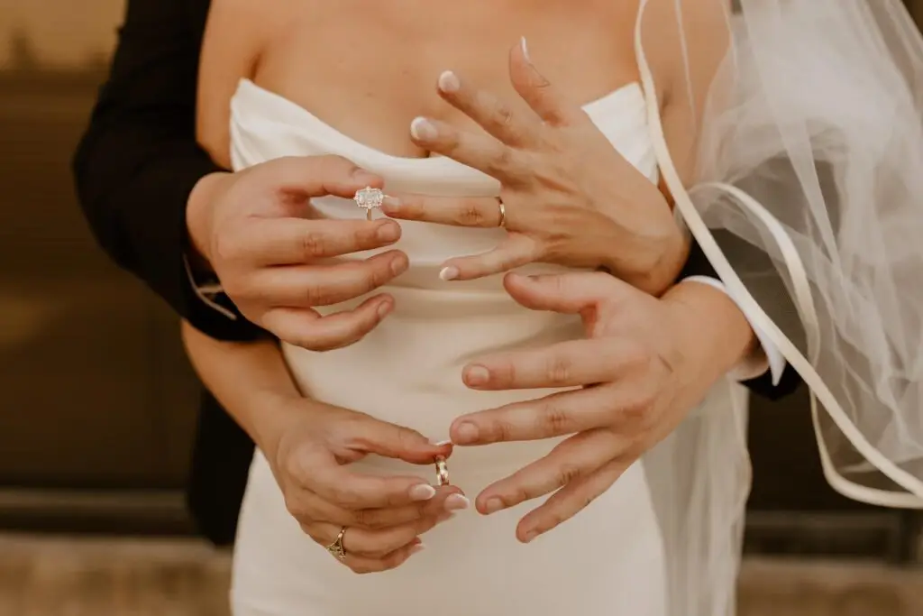 Close-up of bride and groom’s hands showing wedding rings and diamond engagement ring during a Mississippi wedding.